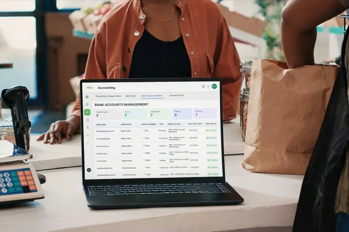 Retail owner at the checkout counter reviewing Flow Keeping on a laptop